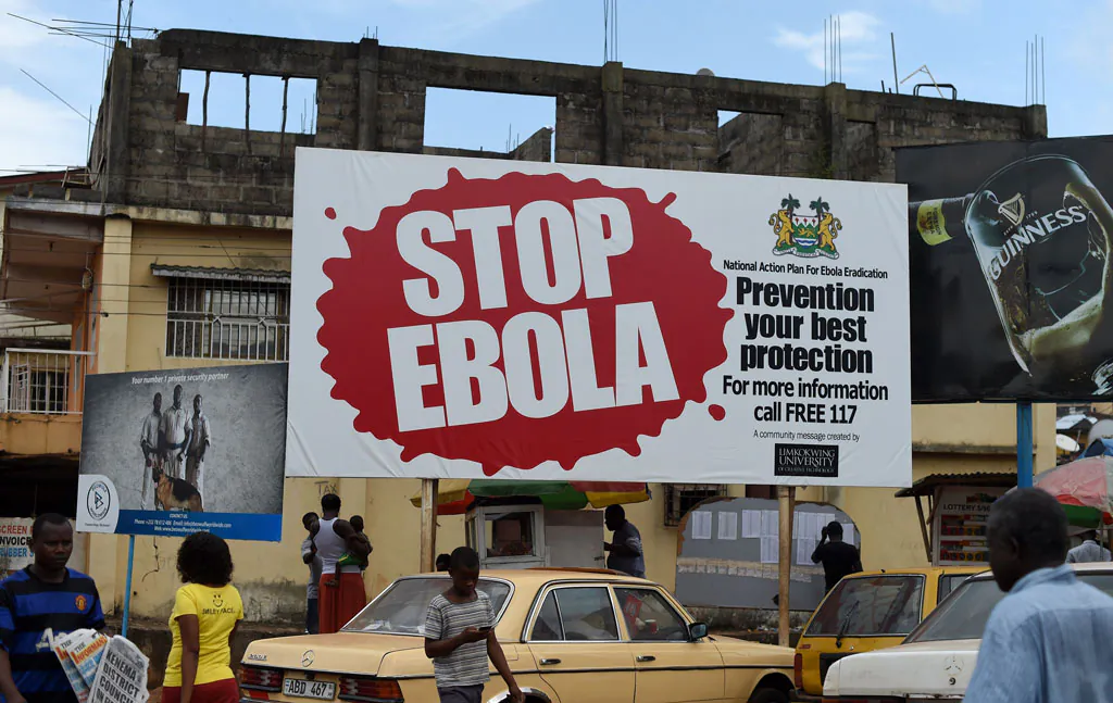 People walk past a billboard with a message about ebola in Freetown, Sierra Leone, on Nov. 7, 2014. (Francisco Leong/AFP/Getty Images)