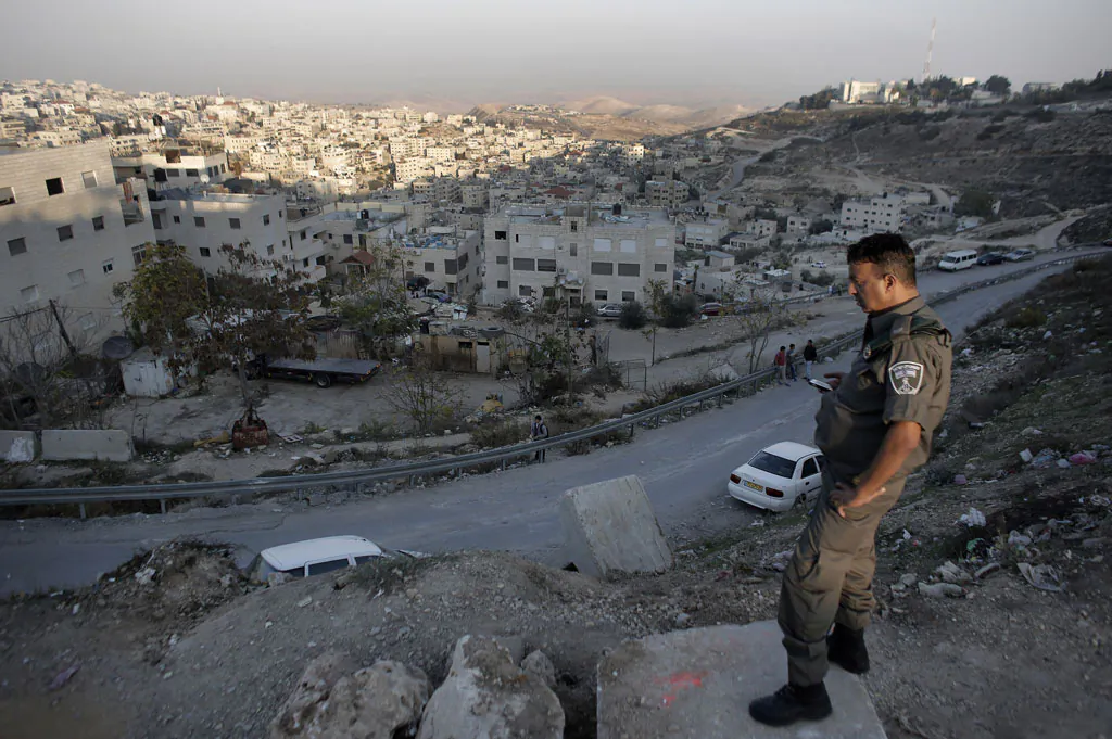 An Israeli policeman stands looking over the flashpoint Arab village of Issawiya (background) in East Jerusalem, during a protest against the new cement blockades at the entrances of the village on Nov. 12, 2014. (Ahmad Gharabli/AFP/Getty Images)