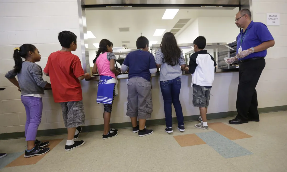 Detained immigrant children line up in the cafeteria at the Karnes County Residential Center, a temporary home for immigrant women and children detained at the border in Karnes City, Texas, on Sept. 10, 2014. (AP Photo/Eric Gay)