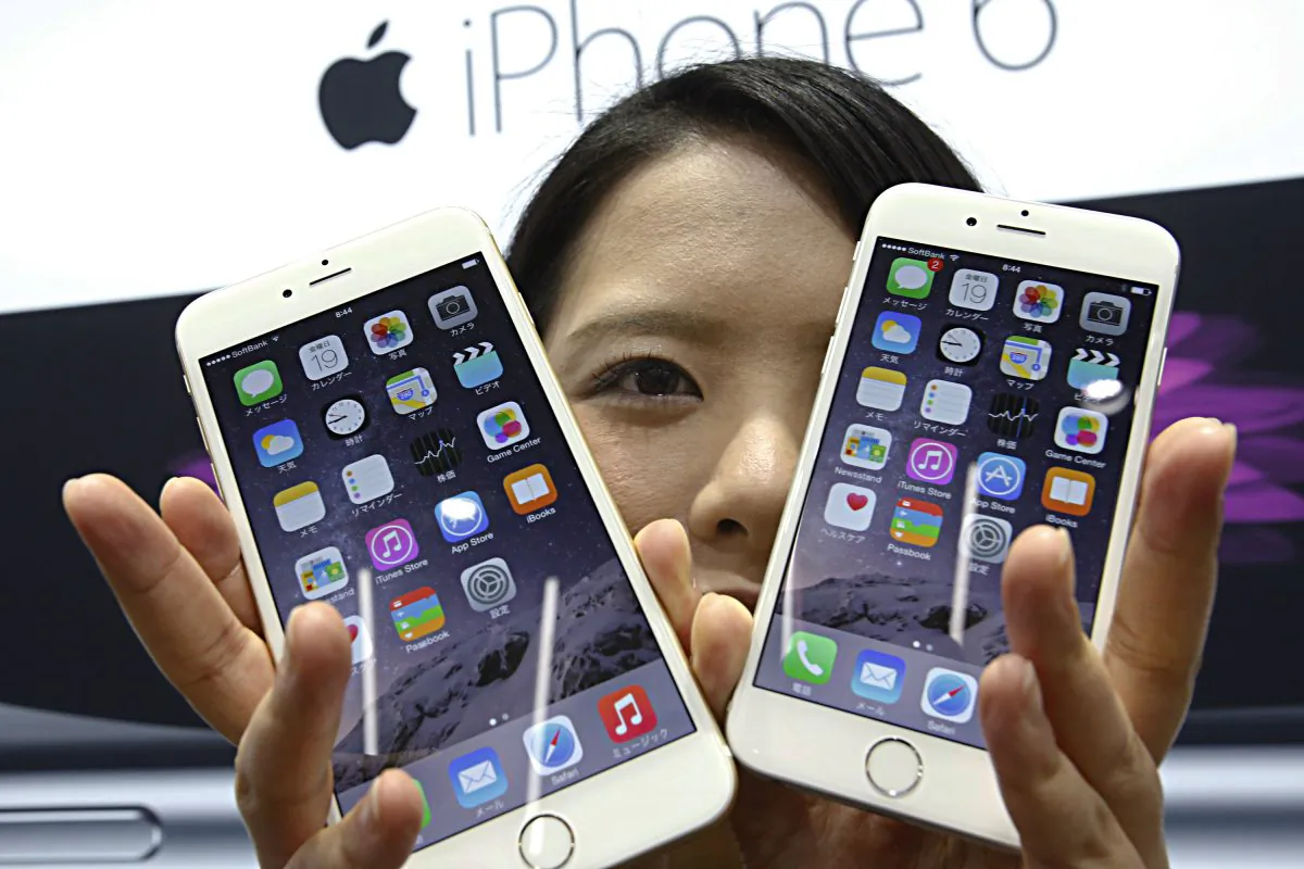 A customer shows off the new Apple iPhone 6 and 6 Plus at a store in Tokyo Friday, Sept. 19, 2014. (Shizuo Kambayashi/AP Photo)