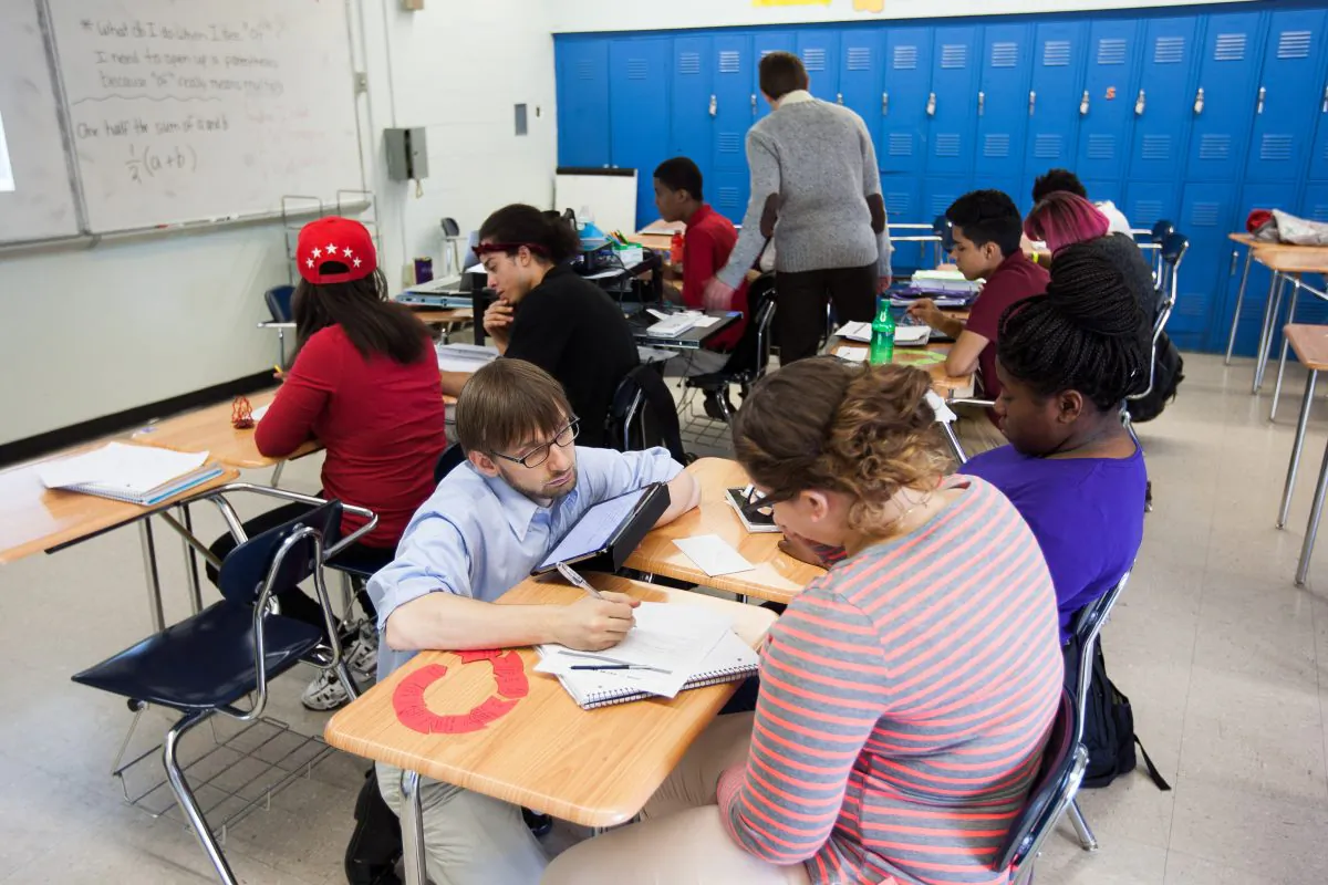 Two teachers help students in a classroom at the MESA Charter High School in Bushwick, Brooklyn, New York, on Oct. 28, 2014. (Petr Svab/Epoch Times)