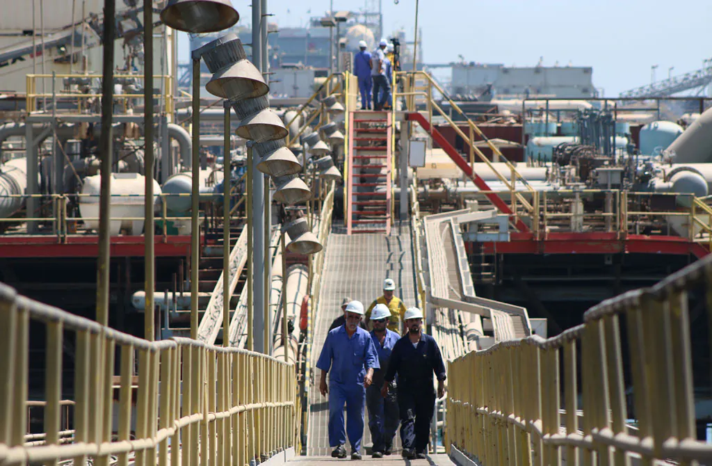 Iraqi labourers walk past an oil tanker docked at a floating platform on Sept. 21, 2014, offshore from the southern Iraqi port city of Al Faw, 90 kilometres south of Basra. (Haidar Mohammed Ali/AFP/Getty Images)