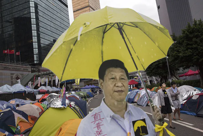 A cardboard cut-out of Chinese president Xi Jinping holding a yellow umbrella, the symbol of the movement, is seen outside a tent used by pro-democracy protesters  at the Admiralty protest site on Nov. 13, 2014, in Hong Kong.  Hong Kong's high court authorized police to arrest protesters who obstruct bailiffs on the three interim restraining orders.  (Photo by Kevin Frayer/Getty Images)
