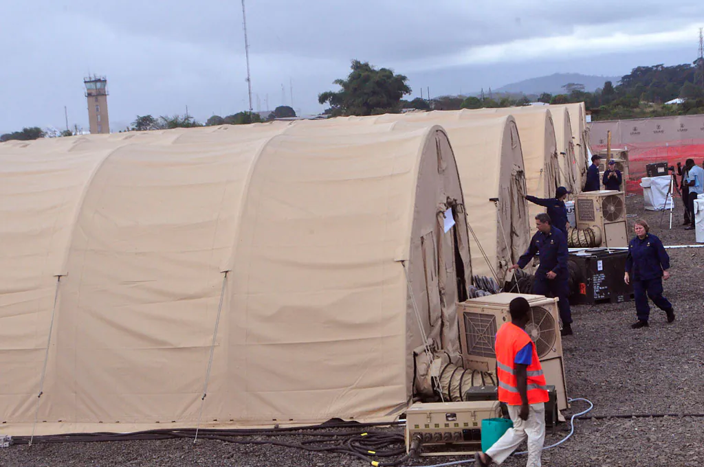 Health workers walk around medical tents that form part of a new American clinic to be used for the treatment of people suffering from the Ebola virus in the outskirts of the city of Monrovia, Liberia, on Nov. 5, 2014. As the Ebola epidemic flares in new hot spots and dims in others, the response to its shifts must catch up, experts say, and that’s a challenge because it is a slow process for governments to authorize aid, to gather it together and then deliver it. And to build treatment units, even rudimentary ones, takes even more time. By the time it’s built, the outbreak may have moved elsewhere. (AP Photo/Abbas Dulleh)