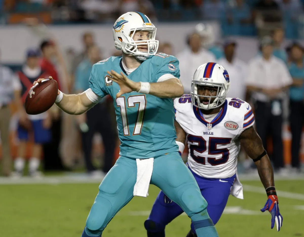 Miami Dolphins quarterback Ryan Tannehill (17) looks for an open receiver as Buffalo Bills strong safety Da'Norris Searcy (25) closes in during the first half of an NFL football game, Thursday, Nov. 13, 2014, in Miami Gardens, Fla. (AP Photo/Alan Diaz)