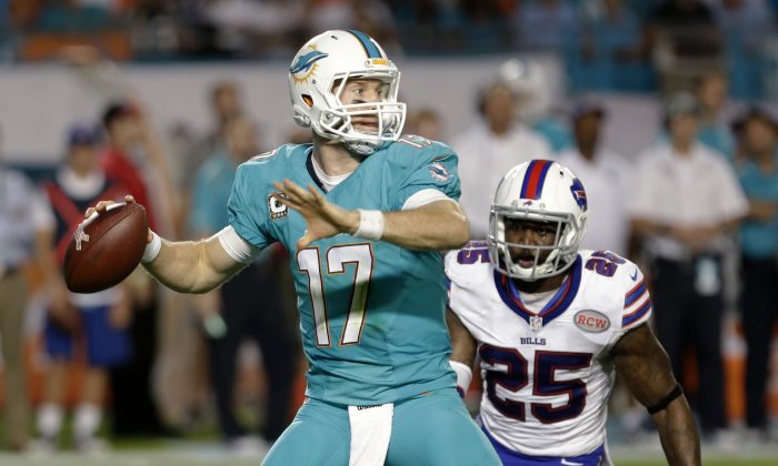 Miami Dolphins quarterback Ryan Tannehill (17) looks for an open receiver as Buffalo Bills strong safety Da'Norris Searcy (25) closes in during the first half of an NFL football game, Thursday, Nov. 13, 2014, in Miami Gardens, Fla. (AP Photo/Alan Diaz)