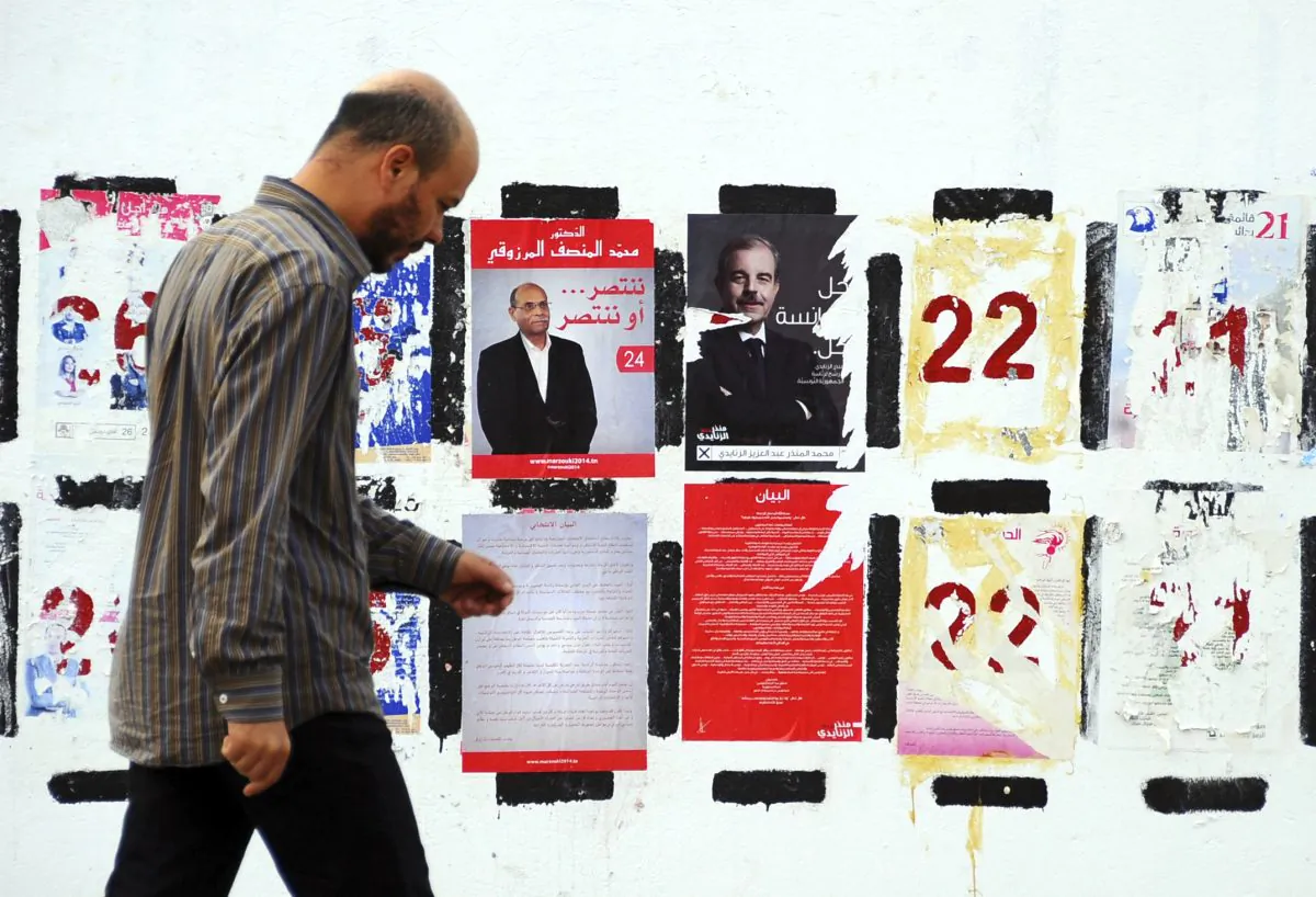 A man walks past electoral posters for the upcoming presidential elections in Tunis on Nov. 5, 2014. Campaign posters and banners for next week’s presidential elections have covered the walls of Tunisia’s cities and towns, papering over the flaking posters from the parliamentary elections just three weeks ago. (AP Photo/Hassene Dridi)