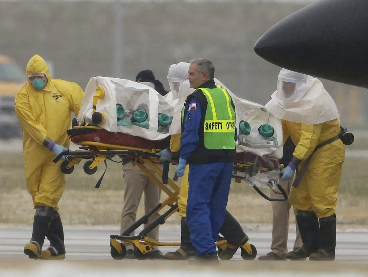 Health workers in protective suits transport Dr. Martin Salia, a surgeon working in Sierra Leone who had been diagnosed with Ebola, from a jet that brought him from Sierra Leone to a waiting ambulance that will take him to the Nebraska Medical Center in Omaha, Neb., Saturday, Nov. 15, 2014. Dr. Salia is the third Ebola patient at the Omaha hospital and the 10th person with Ebola to be treated in the U.S. (AP Photo/Nati Harnik)