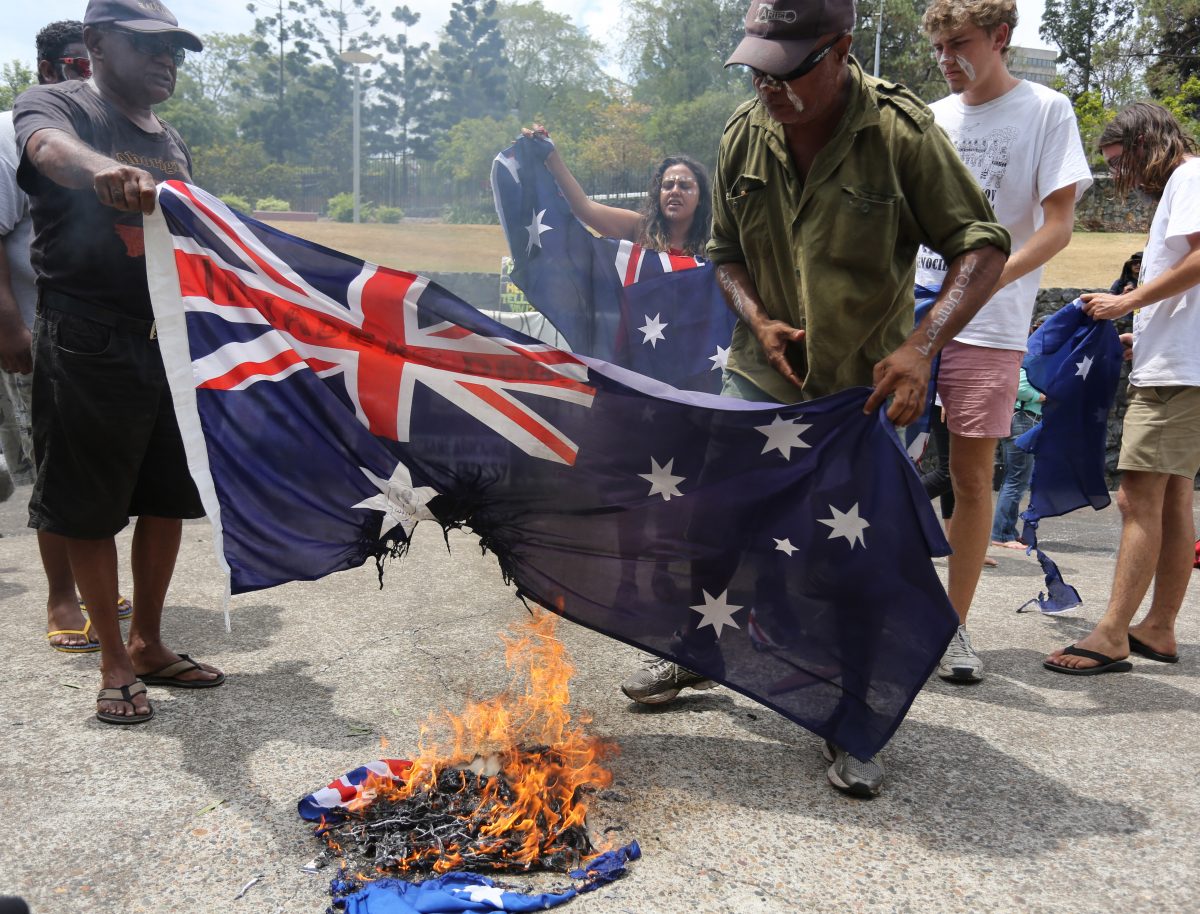 Aboriginal protesters burn an Australian flag during a rally in coincidence with the G-20 summit in Brisbane, Australia, Sunday, Nov. 16, 2014.(AP Photo/Dean Saffron)