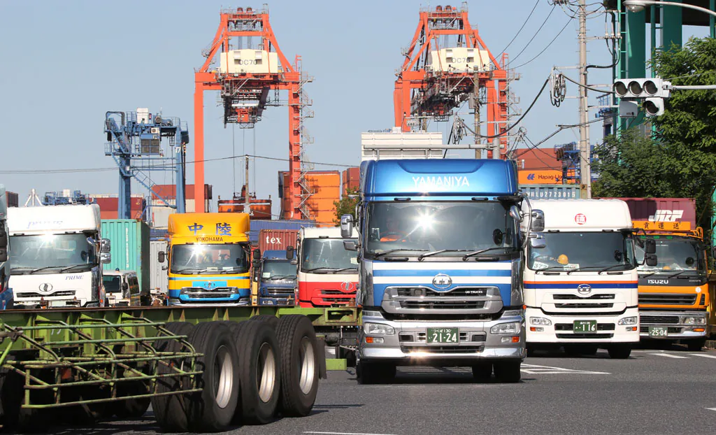 Trucks leave a container wharf in Tokyo on Sept. 26, 2014. Japan reported Monday, Nov. 17, that its economy contracted at a real annual rate of 1.6 percent in July-September in the second straight quarterly decline. Most economists had forecast the world’s third-biggest economy expanded at about a 2 percent pace. The negative growth figure was much lower than expected and makes it very likely Prime Minister Shinzo Abe will delay implementation of a sales tax hike planned for October 2015. (AP Photo/Koji Sasahara)