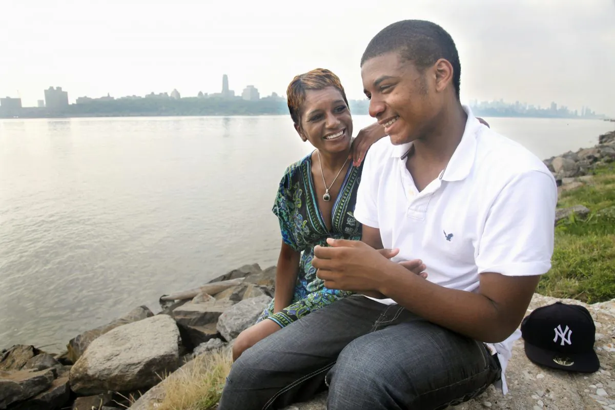 Rachel Noerdlinger and her son Khari, 14, sit at the edge of the Hudson River near their home in Edgewater, N.J., across from Harlem, N.Y., on Tuesday, June 28, 2011. Noerdlinger previously lived in Harlem for 16 years before moving to Edgewater.  (AP Photo/Bebeto Matthews)