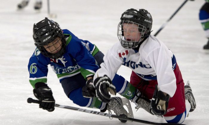 Two kids playing hockey fall to the ice in a novice-level game. Children playing hockey need to have greater respect for their fellow players as a preventative measure against concussions.
(The Canadian Press/Doug Ives)