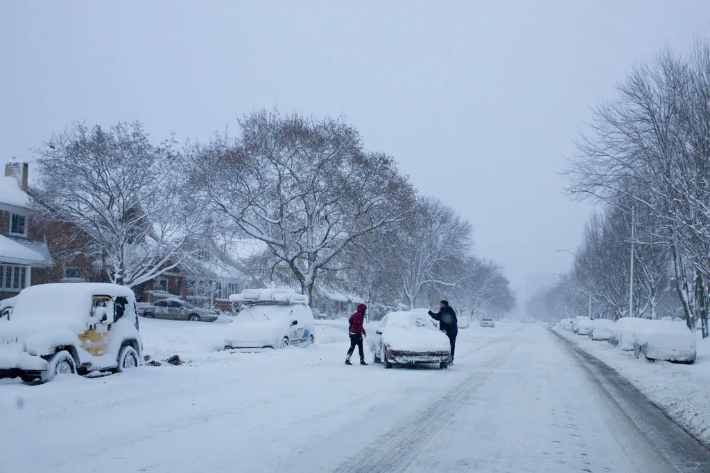 People attempt to move a vehicle out of the middle of the road along Lake Michigan Drive, Tuesday, Nov. 18, 2014, in Grand Rapids., Mich. Michiganians are shivering after a pre-winter cold weather system with gale-force winds broke temperature records and dumped up to foot and a half of snow. (AP Photo/The Grand Rapids Press, Joel Bissell)