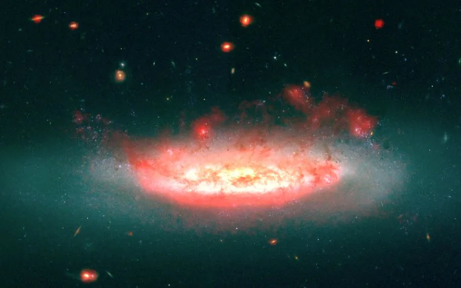 A composite image shows the galaxy NGC 4522 in the Virgo Cluster, the nearest large cluster of galaxies to our own local group of galaxies, and the "wake" of gas and dust being blown from the galaxy. The galaxy appears blue in the Hubble Space Telescope image in visible light. The superimposed red image is from Spitzer data and shows emissions from dust that traces molecular hydrogen. In the image, the galaxy is moving down and into the plane of the photo. (Suresh Sivanandam; Dunlap Institute for Astronomy & Astrophysics)