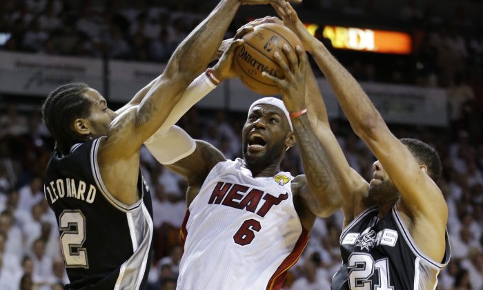 FILE - In this June 10, 2014, file photo, San Antonio Spurs forward Tim Duncan (21) and forward Kawhi Leonard (2) defend against Miami Heat forward LeBron James (6), during the first half in Game 3 of the NBA basketball finals in Miami. They've denied LeBron James winning two NBA titles, and in last year's Finals the Spurs dismantled the Heat, a beatdown that may have hastened the superstar's decision to re-sign with the Cavaliers. On Wednesday, Nov. 19, James faces his nemesis for the first time since June. By(AP Photo/Wilfredo Lee, File)