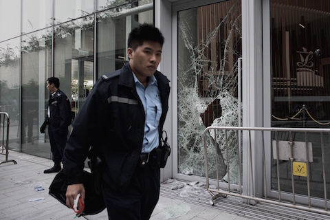 A policeman walks past a broken window of the government headquarters building in the Admiralty district of Hong Kong on November 19, 2014 after a small group attempted to break into the city's legislature. (Philippe Lopez/AFP/Getty Images)