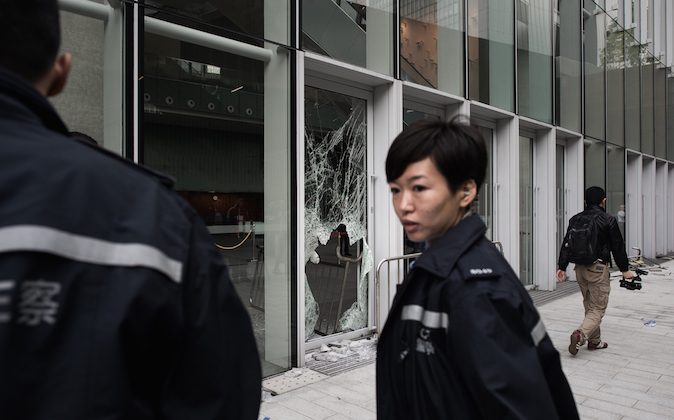 A policewoman stands by a broken window of the government headquarters building in the Admiralty district of Hong Kong on November 19, 2014. (Philippe LopezAFP/Getty Images)