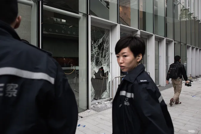 A policewoman stands by a broken window of the government headquarters building in the Admiralty district of Hong Kong on November 19, 2014. (Philippe LopezAFP/Getty Images)