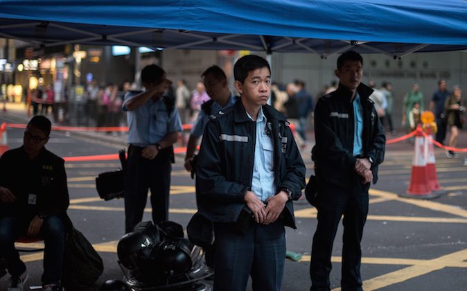 Hong Kong police officers look at a barricade built by pro-democracy protesters in the Mongkok district of Hong Kong on November 19, 2014. Hong Kong police clashed with pro-democracy demonstrators early on November 19 after a small group attempted to break into the city's legislature, with tensions spiking as court-ordered clearances of protest sites get under way.   (Alex Ogle/AFP/Getty Images)