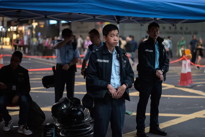 Hong Kong police officers look at a barricade built by pro-democracy protesters in the Mongkok district of Hong Kong on November 19, 2014. Hong Kong police clashed with pro-democracy demonstrators early on November 19 after a small group attempted to break into the city's legislature, with tensions spiking as court-ordered clearances of protest sites get under way. (Alex Ogle/AFP/Getty Images)