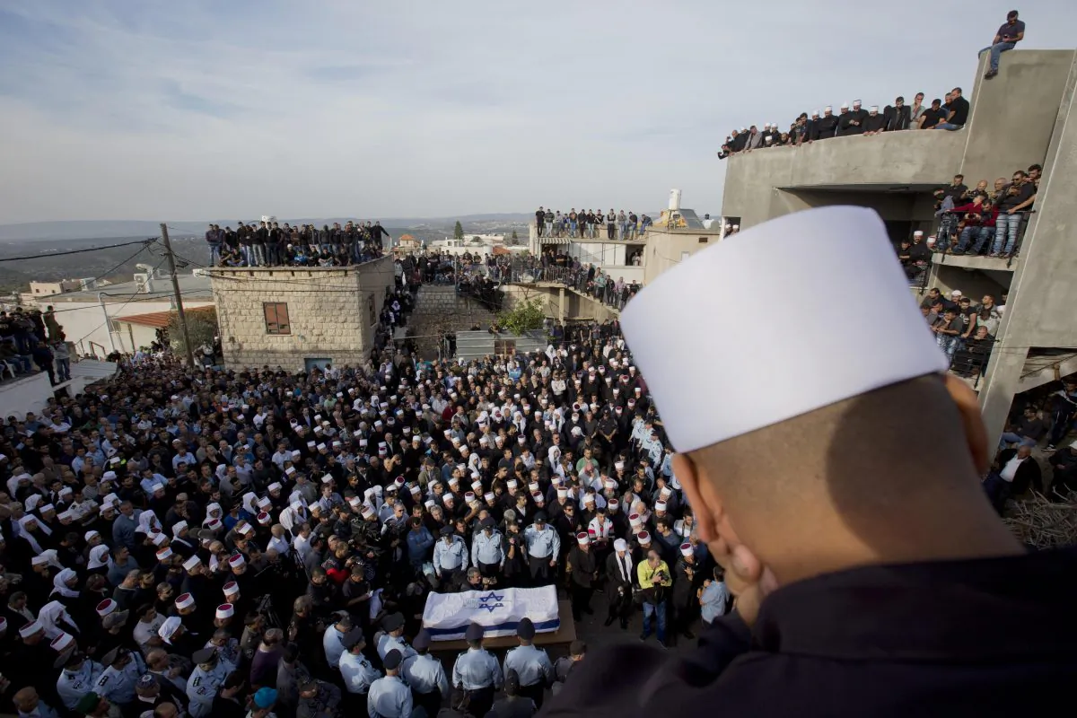 A Druze man watches as others surround the flag draped coffin during the funeral of Druze Israeli police officer Zidan Sif in the Druze village of Yanuh-Jat, northern Israel, Wednesday, Nov. 19, 2014. Sif, 30, died of his wounds on Tuesday after Two Palestinian cousins armed with meat cleavers and a gun stormed a Jerusalem synagogue during morning prayers Tuesday, killing four people in the city’s bloodiest attack in years. Police killed the attackers in a shootout. (AP Photo/Ariel Schalit)
