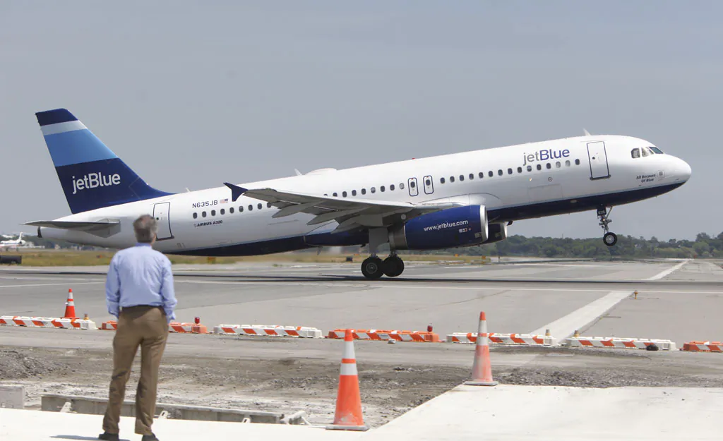 A man watches a JetBlue airplane take off from John F. Kennedy International Airport in New York on June 2, 2010. JetBlue Airways Corp. on Wednesday, Nov. 19, 2014, said that it will create three ticket classes, and only the top two include at least one free checked bag. The company didn't say what the bag fee would be for the cheapest flights. (AP Photo/Seth Wenig)