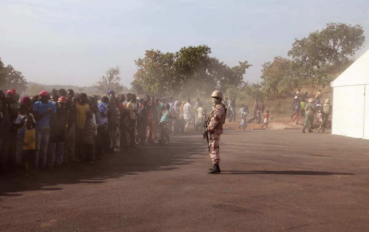 A Mali soldier (C) controls a crowd of people during a visit by their president, Ibrahim Boubacar Keita, at the border village of Kouremale, Mali, between Mali and Guinea, on Nov. 17, 2014. On Mali's dusty border with Ebola-stricken Guinea, travelers have a new stop: Inside a white tent, masked medical workers zap incomers with infrared thermometer guns and instruct them to wash their hands in chlorinated water. (AP Photo/Baba Ahmed)