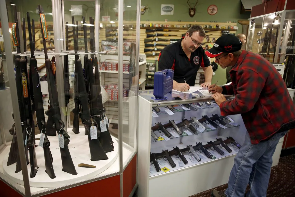 In this Saturday, Nov. 15, 2014 photo, Steven King, left, fills out paperwork before selling a handgun to first-time gun owner Dave Benne at Metro Shooting Supplies, in Bridgeton, Mo. King says he’s sold two to three times more weapons in recent weeks than normal as a grand jury decides whether to indict Ferguson police Officer Darren Wilson in the shooting death of Michael Brown. (AP Photo/Jeff Roberson)