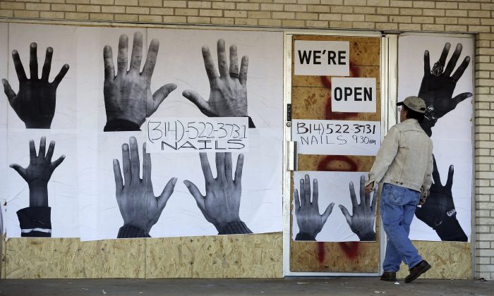 A man who declined to be identified stands outside a boarded up business Thursday, Nov. 20, 2014, in Ferguson, Mo. (AP Photo/Jeff Roberson)
