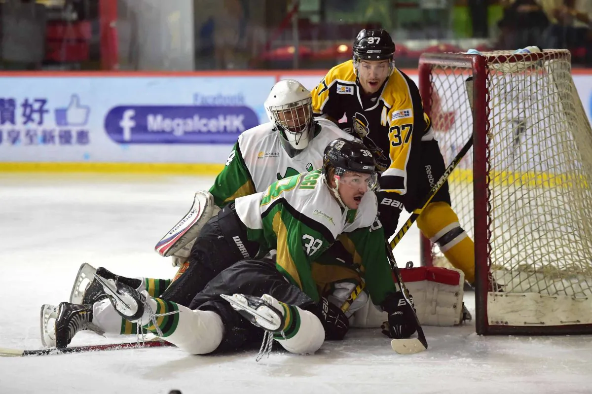 Jeff Ceccacci of Macau Aces helps goalie Emerson Keung to ward off an attack by Kory Falite of Hong Kong Tycoons in their CIHL match at Mega Ice on Saturday Nov 15, 2014. (Bill Cox/Epoch Times)