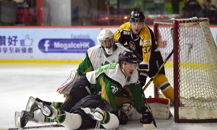 Jeff Ceccacci of Macau Aces helps goalie Emerson Keung to ward off an attack by Kory Falite of Hong Kong Tycoons in their CIHL match at Mega Ice on Saturday Nov 15, 2014. (Bill Cox/Epoch Times)