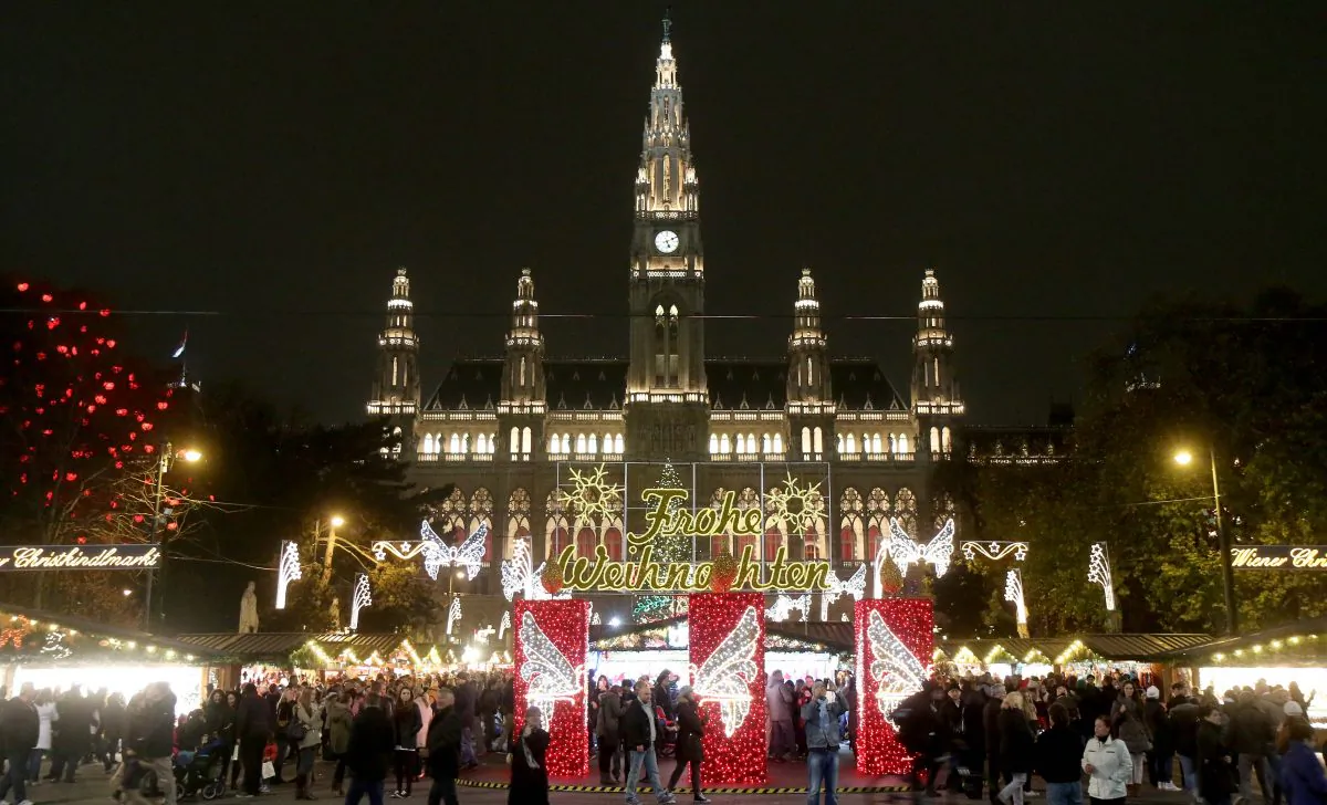 In this picture taken Sunday, Nov. 16, 2014 visitors crowed the Christmas market in front of the neo-Gothic City hall in Vienna, Austria. Nothing will put you more in the mood for the festive season than the Christmas markets big and small dotting the city. Choices range from the more than 150 wooden huts set up in front of the City hall, to markets often no bigger than a few booths. Among the hundreds of goods on offer are tree lights, candles, ornaments and musical Christmas toys. Letters read "Merry Christmas". (AP Photo/Ronald Zak)