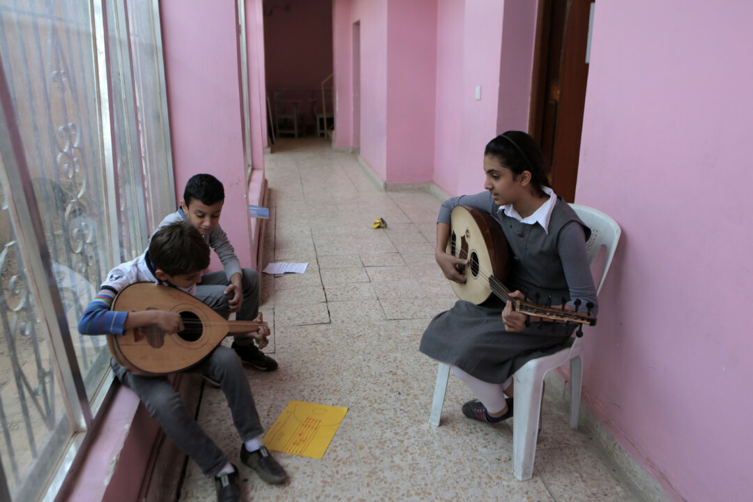 In this Nov. 12, 2014, photo, students practice music in the hallway because of limited classrooms at the Baghdad School of Music and Ballet in Monsur district in Baghdad. The school was looted days after Saddam Hussein's ouster. Later it was partially burned during a rampage by disgruntled Saddam-era officers. (AP Photo/Khalid Mohammed)
