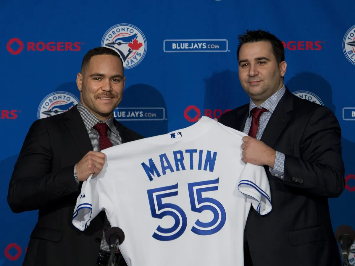 Toronto Blues Jays newly-signed catcher Russell Martin, left, and general manager Alex Anthopoulos hold up a jersey during a baseball press conference in Toronto, Thursday, Nov. 20, 2014. (AP Photo/The Canadian Press, Nathan Denette)