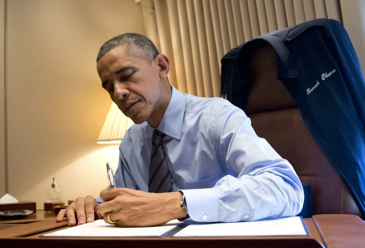 President Barack Obama signs two presidential memoranda associated with his actions on immigration in his office on Air Force One as he arrives at McCarran International Airport in Las Vegas, Friday, Nov. 21, 2014, before traveling to Del Sol High School to speaks about the steps he will be taking on immigration. (AP Photo/Carolyn Kaster)