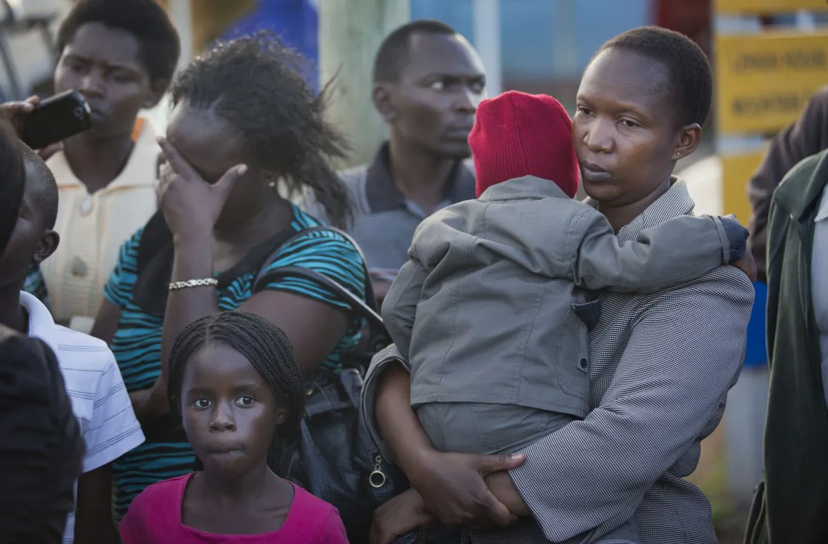 Relative Ziporah Mora (R) holds her child whom she declined to name, as she waits for news of the return of the bodies of those killed in the Mandera attack, with other relatives at Wilson Airport in Nairobi, Kenya, Saturday, Nov. 22, 2014. Somalia's Islamic extremist rebels, al-Shabab, claimed responsibility for the Saturday dawn attack on a bus in the northern Kenyan town of Mandera, near the Somali border, in which 28 non-Muslims were singled out and killed. (AP Photo/Ben Curtis)