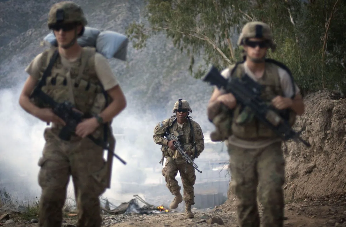 U.S. Army Pfc. Garrick Carlton, center, of Sacramento, Calif., hikes past burning rubbish to man a hilltop observation post along with fellow Pfc. Michael Tompkins, of Wadsworth, Ohio, left, and Pfc. Austin D'Amica, of San Diego, at Combat Outpost Monti in Kunar province, Afghanistan, on Sept. 10, 2011. U.S. officials say President Barack Obama has quietly approved guidelines in recent weeks to allow the Pentagon to target Taliban fighters in Afghanistan, broadening previous plans that had limited the military to counterterrorism missions against al-Qaida after 2014. (AP Photo/David Goldman)