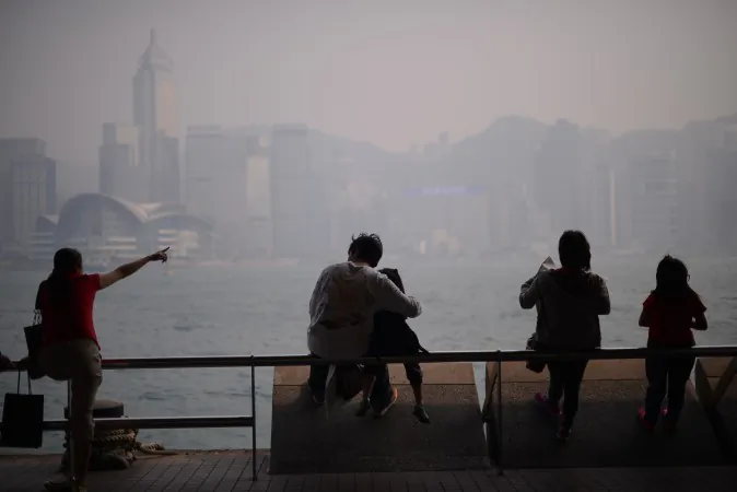 People sit in front of the city's skyline shrouded in a dense blanket of toxic smog in Hong Kong on April 15, 2013. (Philippe Lopez/AFP/Getty Images)