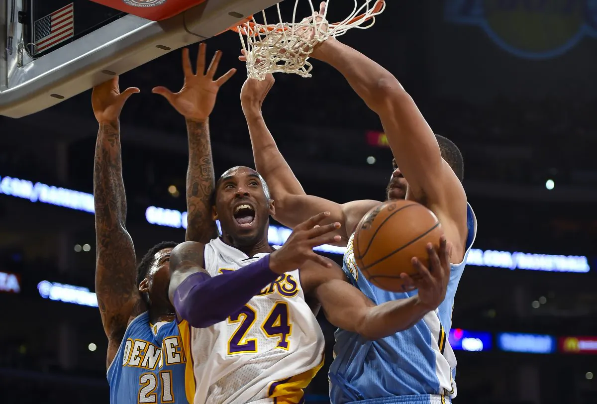 Los Angeles Lakers guard Kobe Bryant, center, gets double teamed by Denver Nuggets forward Wilson Chandler (21) and center JaVale McGee, right, as he drives to the basket in the first half of an NBA basketball game, Sunday, Nov. 23, 2014, in Los Angeles. (AP Photo/Gus Ruelas)
