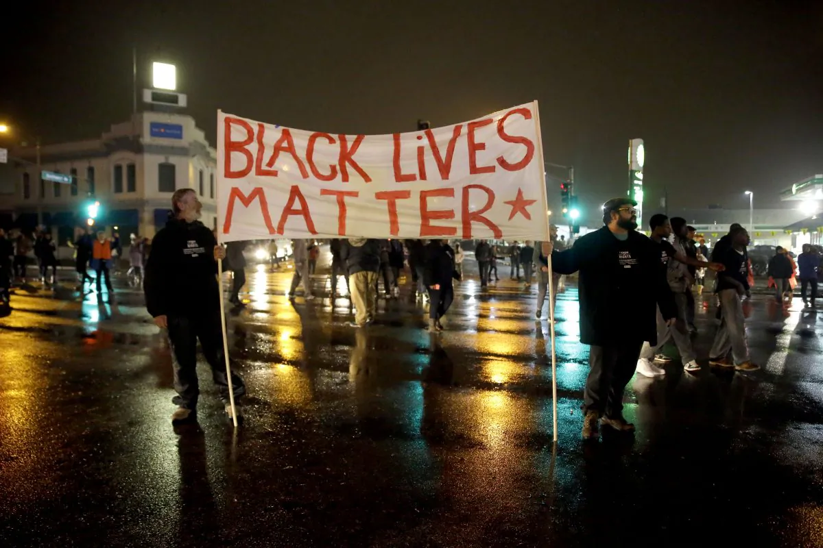 Protesters stand in the middle of a busy intersection blocking traffic Sunday, Nov. 23, 2014, in St. Louis. Ferguson and the St. Louis region are on edge in anticipation of the announcement by a grand jury whether to criminally charge officer Darren Wilson in the killing of 18-year-old Michael Brown. (AP Photo/Jeff Roberson)