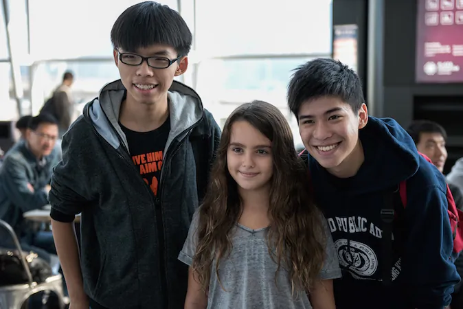 Hong Kong democracy protest leaders Joshua Wong (L) and Lester Shum (R) pose for a photo with a young girl, before fellow student leaders try to board a flight to Beijing, at Hong Kong's international airport on November 15, 2014. Three Hong Kong pro-democracy protest leaders were unable to leave the city for a planned trip to Beijing in hopes of bringing their demands for political reform to Chinese authorities. (Alex Ogle/AFP/Getty Images)