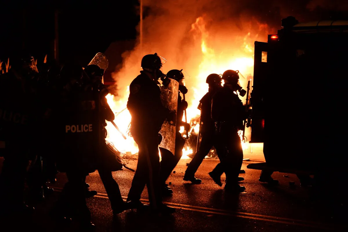 Police chase demonstrators passing a burning police vehicle during clashes between police and protesters over the decision in the shooting death 18-year-old Michael Brown in Ferguson, Missouri, on November 24, 2014. (AFP/Getty Images)