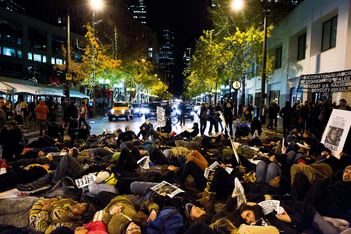 A large group of protestors stage a "die-in" on the street in response to the Ferguson grand jury decision not to indict police officer Darren Wilson in the death of Michael Brown, Monday, Nov. 24, 2014, in Seattle. (AP Photo/seattlepi.com, Jordan Stead)