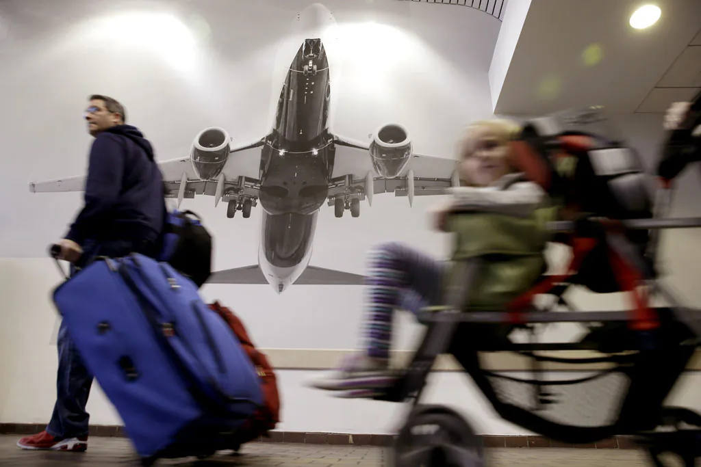 Travelers pass a large photograph of an airplane at LaGuardia Airport in New York, Tuesday, Nov. 25, 2014. A nor'easter was expected to develop along the East Coast just as millions of travelers head to their Thanksgiving destinations, bringing mostly rain close to the coast, but heavier snow further inland. (AP Photo/Seth Wenig)