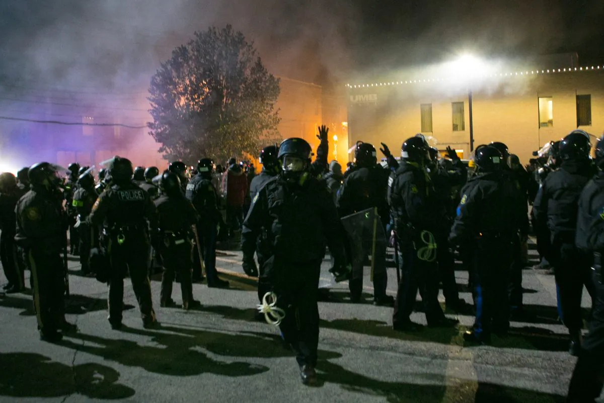 Police in riot gear push everyone, including all media, back away from smoke that is arising around a building in Ferguson, Mo., on Nov. 25, 2014. (Benjamin Chasteen/Epoch Times)