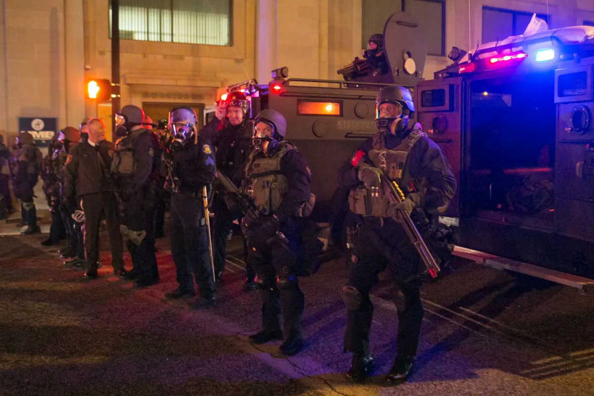 Police in full on riot gear stand by after they fired tear gas at activists not too long before in Ferguson, Mo., on Nov. 25, 2014. (Benjamin Chasteen/Epoch Times)
