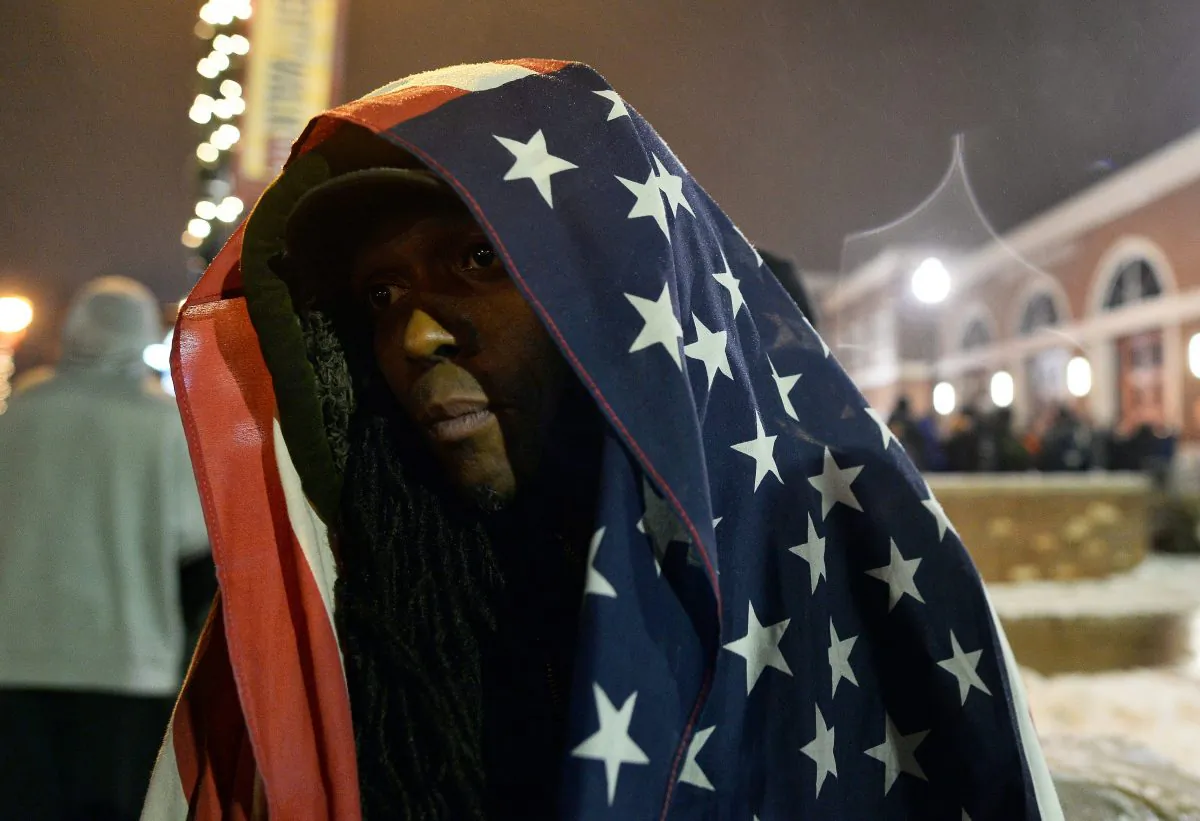 A protester covers himself with a US flag during a demonstration outside the police station in Ferguson, Mo., on Nov. 26, 2014. (Jewel Samad/AFP/Getty Images)