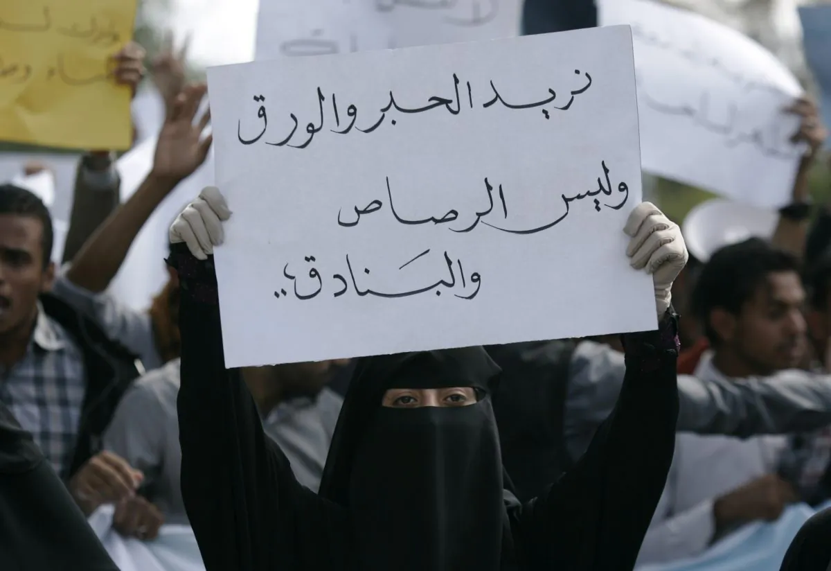 A student holds a banner with Arabic that reads, "we want ink and pens not bullets and rifles," to protest against the Shiite insurgency during a rally at the University of Sanaa, Yemen, Tuesday, Nov. 25, 2014. (AP Photo/Hani Mohammed)