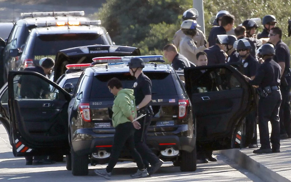 A protestor is handcuffed and taken away by a police officer after the arrest of a small group of protesters who sat down in a bus lane alongside the U.S. 101 near downtown Los Angeles on Nov. 26. Los Angeles Police Chief Charlie Beck says a total of nine people were arrested at the morning protest. (Nick Ut/AP Photo)