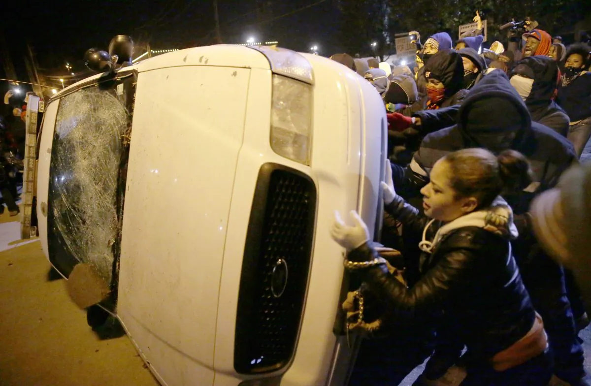 Protesters vandalize a police vehicle outside of the Ferguson city hall in Tuesday, Nov. 25, 2014, in Ferguson, Mo. Missouri's governor ordered hundreds more state militia into Ferguson on Tuesday, after a night of protests and rioting over a grand jury's decision not to indict police officer Darren Wilson in the fatal shooting of Michael Brown, a case that has inflamed racial tensions in the U.S. (AP Photo/David Goldman)